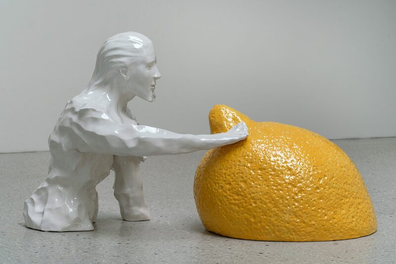 Zu sehen ist das Werk Wayfarers (surf) von Markus Karstieß. Hier sieht man eine menschliche Halbfigur aus Keramik mit einer übergroßen gelben Zitrone