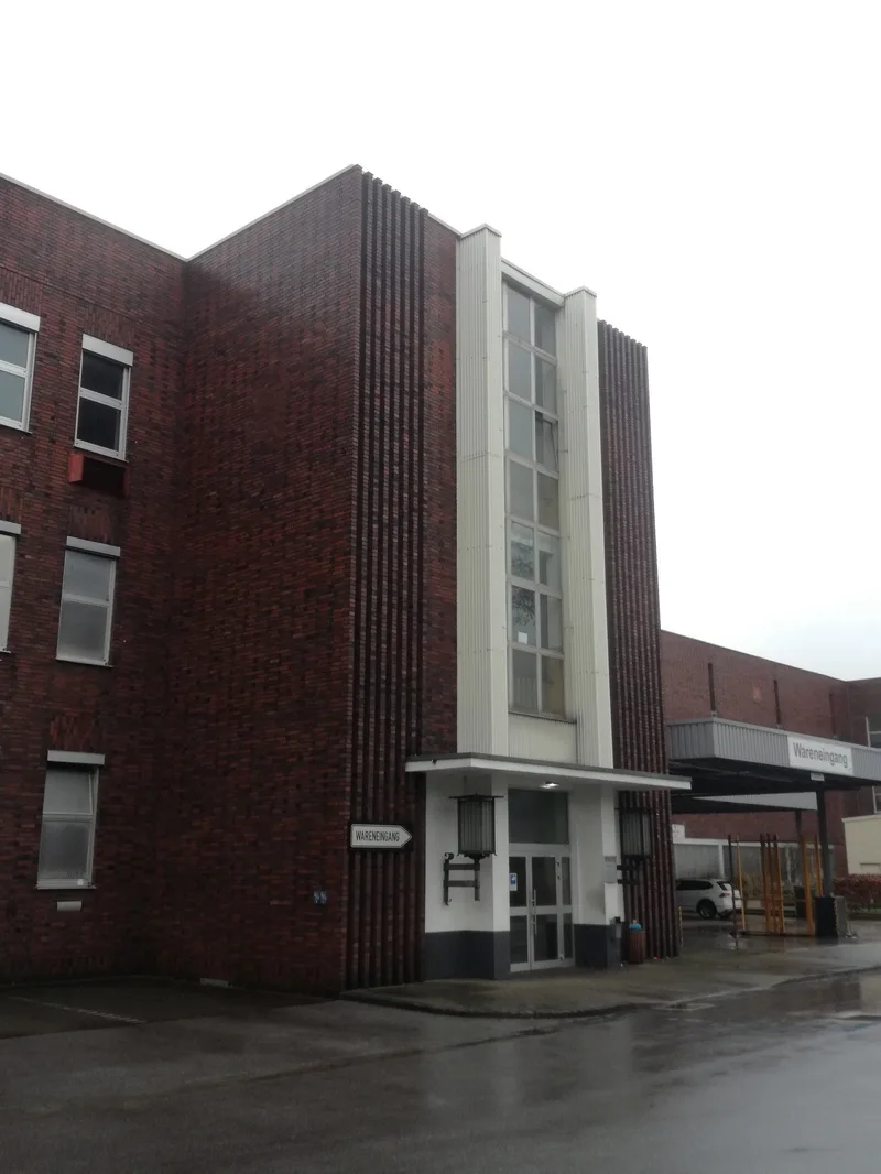 Eingang einer Werkhalle mit dunkler Fassade und hellem vorspringendem Mittelteil