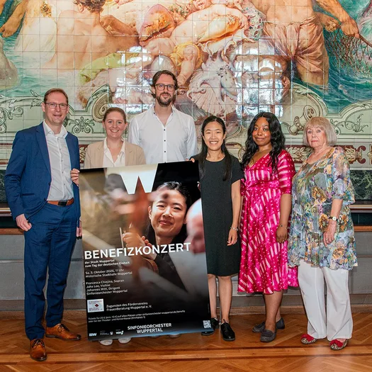 Orchesterdirektor Raimund Kunze, Oberbürgermeisterin Miriam Scherff, Gastdirigent Johannes Witt, Jaha Lee und Francesca Chiejina, Solistinnen des Konzerts, und Gisela Heidelberg-Leske vom Förderverein FrauenBeratung mit dem Plakat zum Festkonzert Deutsche Einheit am 3. Oktober