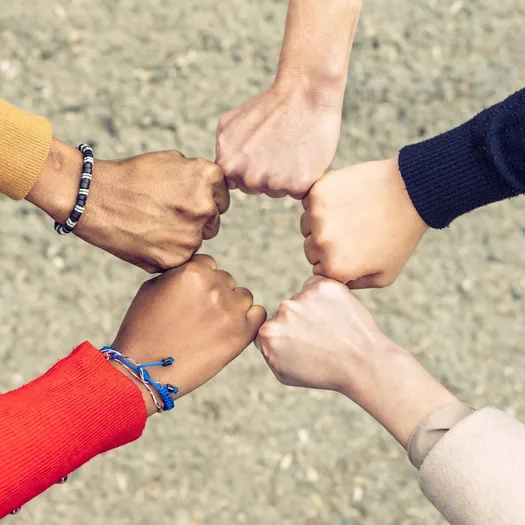 Fünf Hände kommen als Fäuste zusammen und bilden ein Fünfeck