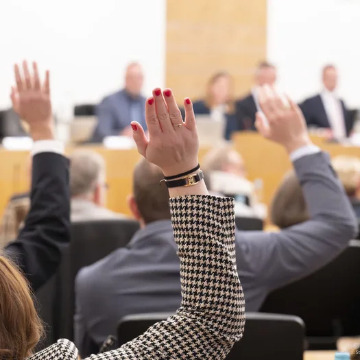 Ein Ratsmitglied hebt die Hand im Ratssaal Wuppertal.