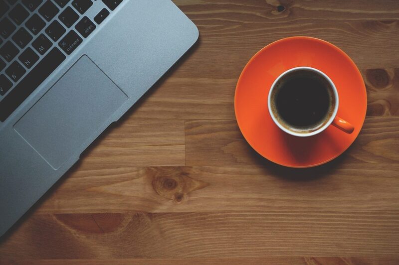 Laptop und Tasse mit Kaffee auf Schreibtisch